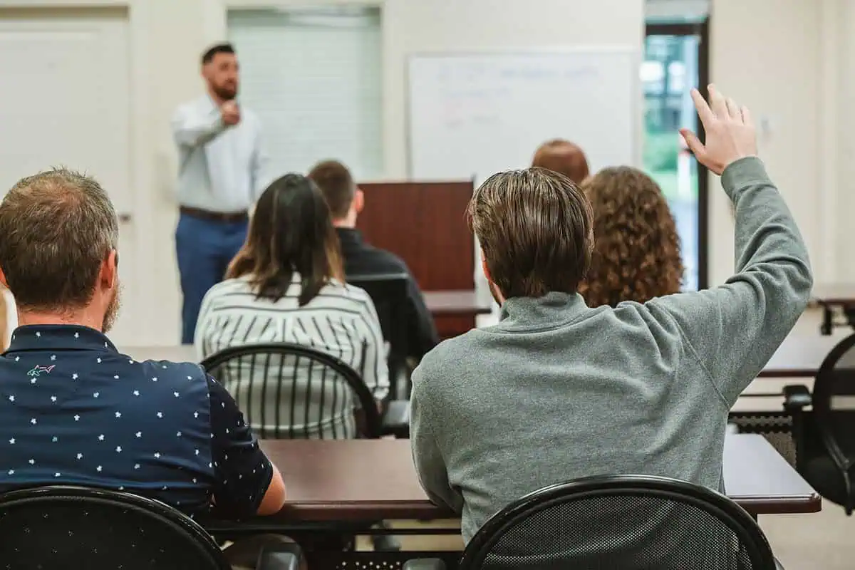 man raising hand in classroom